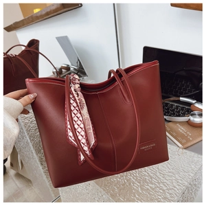 Détail du sac cabas en cuir bordeaux avec foulard en soie imprimé et étiquette logo