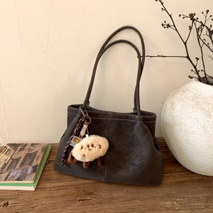 Detail view of retro matte suede tote bag with contrast stitching and plush charm