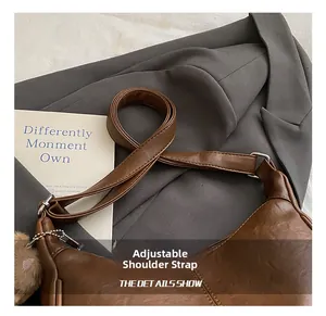 Brown leather tote detail with adjustable shoulder strap and a cute plush ball charm