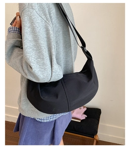 Black crescent dumpling bag with adjustable strap shown on shoulder for daily commute style