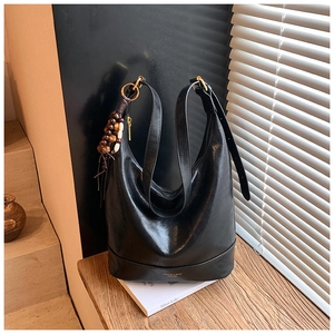 Detail der schwarzen Hobo-Tasche mit braunen Holzperlen-Anhängern und goldenen Beschlägen