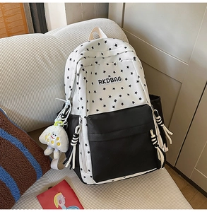 Detail of cute star pattern backpack with RKDBAG logo and white plush pendant on a sofa
