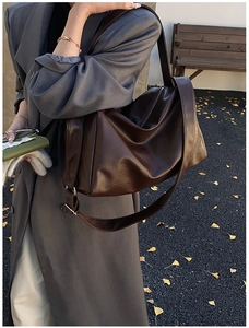 Detail der braunen Vintage-Schultertasche aus weichem Leder vor herbstlichem Hintergrund