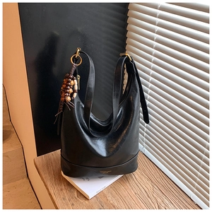 Detail der schwarzen Hobo-Tasche aus Wachsleder mit Goldbuchstaben und Perlenquaste