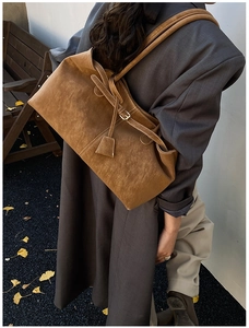 Détail d'un grand sac cabas en daim marron avec sangles à boucles et étiquette en cuir