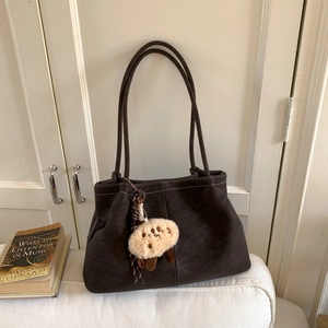 Close-up of a vintage dark brown matte shoulder bag with a cute plush animal charm