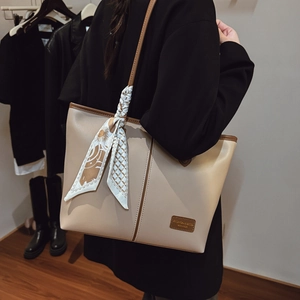 Détail d'un grand sac fourre-tout beige avec bandoulière et foulard décoratif en soie