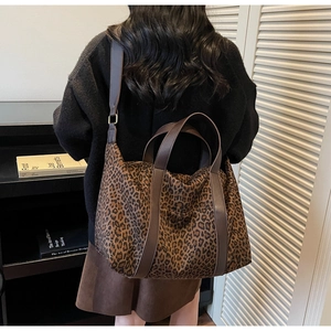 Detailed view of large leopard print tote bag with brown leather handles and shoulder strap