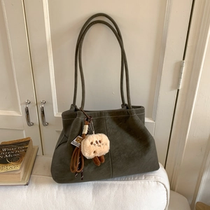 Detail of vintage olive green faux leather bag with contrast stitching and plush charm