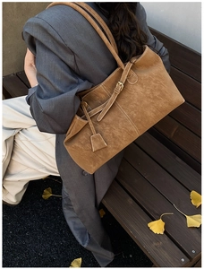 Détail du cabas en daim caramel avec surpiqûres beiges et boucle décorative latérale
