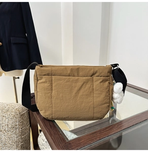 Gros plan détaillé du sac seau en nylon marron avec sangle noire et pompon blanc