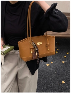 Caramel oil-wax leather tote bag detail with gold turn-lock and chocolate charm