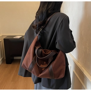 Close-up of brown suede tote bag with contrast leather straps worn by a model