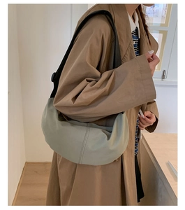 Detailed view of sage green crescent bag with reinforced stitching and black strap