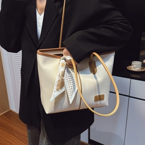 Détail du sac cabas crème avec anses marron et accessoire foulard en soie à motifs élégants