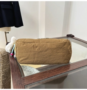 Détail du fond d'un sac seau en nylon marron avec coutures soignées et logo en métal de marque