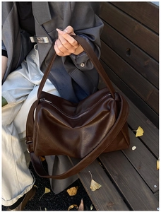 Detail einer dunkelbraunen Boston-Tasche aus glänzendem Leder mit breitem Trageriemen