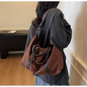 Brown matte leather tote bag with long straps worn over the shoulder by a model