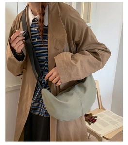 Light green crescent crossbody bag styled with a beige trench coat for a casual daily look