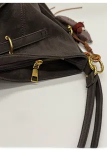 Detailaufnahme des goldenen Reißverschlusses und Leder-Schultergurts am Wildleder-Shopper