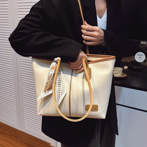 Grand sac cabas crème avec bordure marron et foulard en soie porté à l'épaule