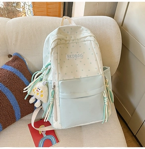 Detail of light blue star print backpack with plush charm on a cozy corduroy sofa