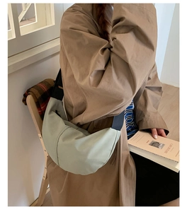Close-up of light green crescent nylon crossbody bag worn by model showing its 3D profile