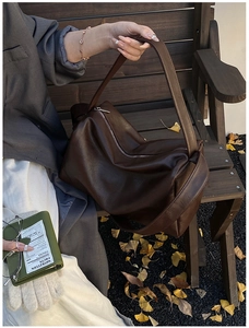 Detail einer großen dunkelbraunen Tasche aus weichem Leder mit breitem Schultergurt