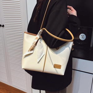 Grand sac cabas crème avec bordure en cuir marron et foulard porté par un mannequin