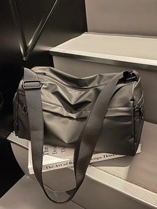 Minimalistische große schwarze Umhängetasche für Damen auf einer modernen Treppe präsentiert