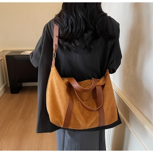 Detail view of caramel suede tote bag with brown leather handles on a model