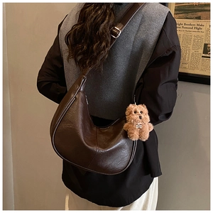 Detail of dark brown faux leather tote bag with a cute plush bear charm on a strap