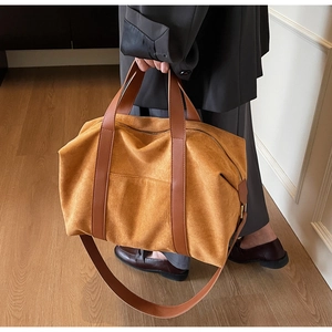 Detail of a large mustard suede tote bag with brown leather handles in a warm interior