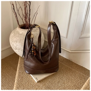 Nahaufnahme braune Vintage-Beuteltasche mit Holzperlen-Quaste auf gewebtem Teppich