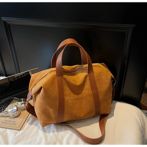 Detail of a brown suede tote bag on a white bed with a laptop and headphones