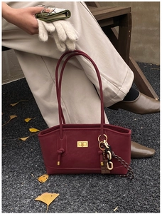 Close-up of a burgundy oil wax leather tote bag with gold metal lock and retro accents