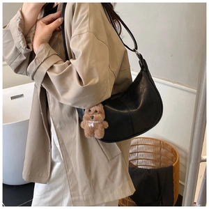 Detail of black hobo bag in grainy leather with a cute plush bear charm for daily wear