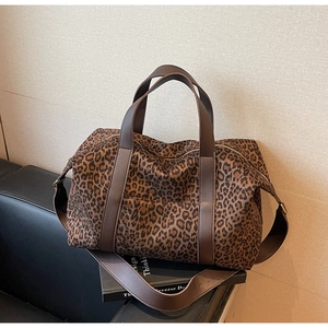 Close-up of leopard print travel tote bag featuring brown faux leather handles and strap