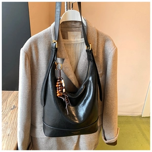 Detail der schwarzen Hobo-Tasche aus Leder mit Holzperlen-Quaste und goldener Hardware