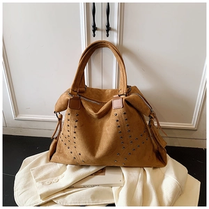 Detailaufnahme der braunen Wildleder-Tragetasche mit Metallnieten und langen Fransen