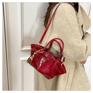 Dettaglio borsa rossa motivo coccodrillo con ciondolo di perline su cappotto in tweed beige