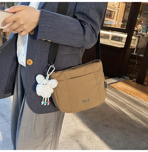 Détail du sac seau en nylon marron avec bandoulière noire et breloque agneau en peluche