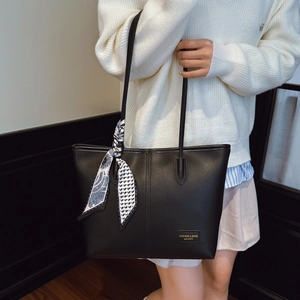 Détail d'un sac cabas en cuir noir avec logo doré et décor d'écharpe en soie bleue