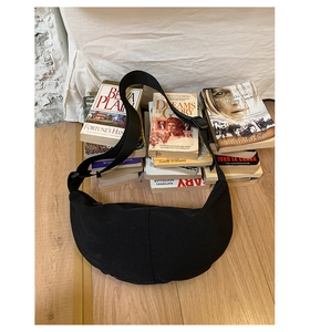 Detailed macro of the black crescent crossbody bag with adjustable wide strap and zipper