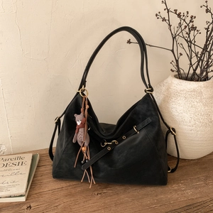 Nahaufnahme schwarze Hobo-Tasche aus Wildleder mit Ösenriemen und süßem Bären-Anhänger