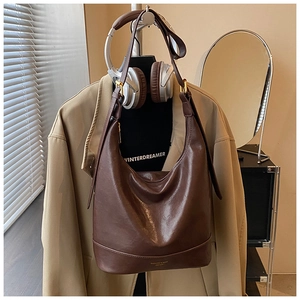 Detail einer dunkelbraunen Ledertasche mit goldener Schnalle in Büroumgebung