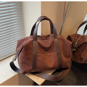 Detail of dark brown matte suede tote bag with vintage bronze hardware and leather handles