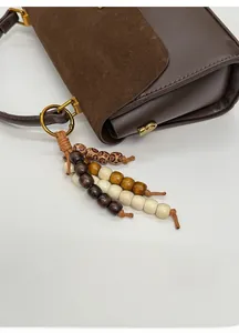 Détail du sac à main marron avec pendentif en perles de bois et boucles en métal doré