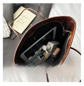 Top view of spacious interior of dark brown leather tote bag with various daily essentials