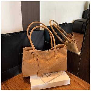 Vue détaillée de la texture en daim marron et de la sangle décorative du sac cabas